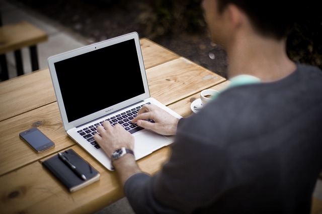 Homme assis devant un ordinateur portable, mains sur le clavier