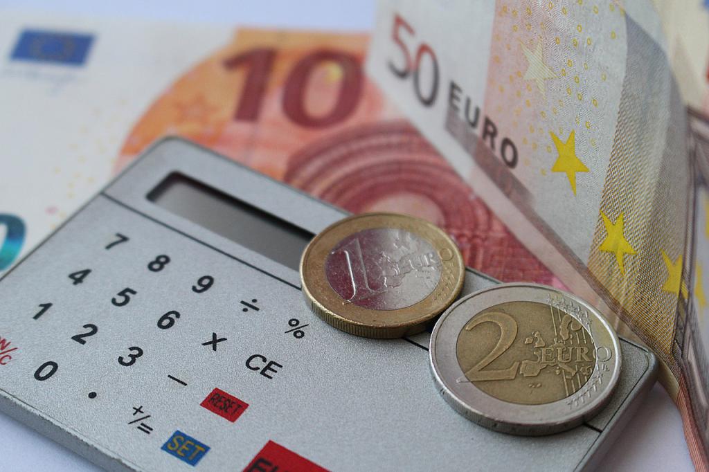 Calculatrice placée au milieu de pièces de monnaie et de billets de banque (€)
