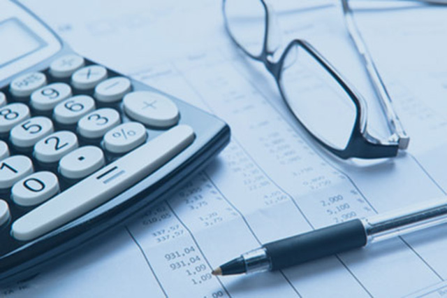 Une calculatrice, des lunettes et un stylo à bille posés sur un feuille de papier contenant des chiffres