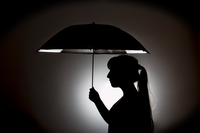 Silhouette d'une jeune femme tenant un parapluie
