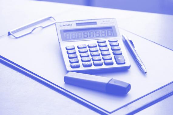 Calculatrice, stylo à bille et surligneur fluo posés sur un porte bloc-notes