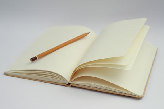 Crayon posé sur un carnet de notes ouvert à une page blanche