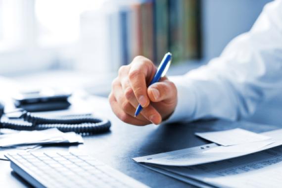 Main d'un homme qui tient un stylo sur son bureau