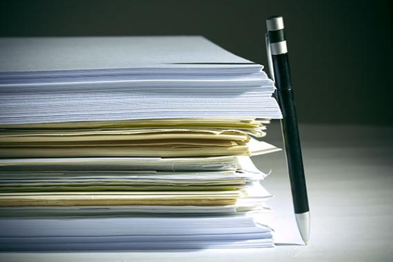 Stylo à bille appuyé sur une pile de papiers