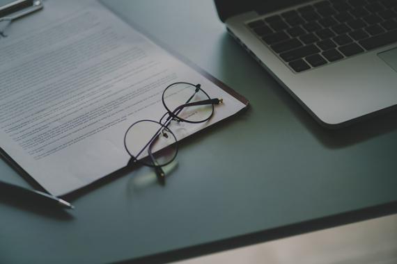 Paire de lunettes posée sur un document à côté d'un ordinateur