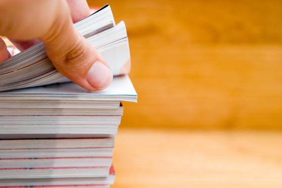 Main ouvrant un cahier dans une pile de documents