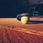 Raquette de tennis au sol reposant sur une balle de tennis